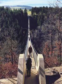 People walking on footbridge in forest