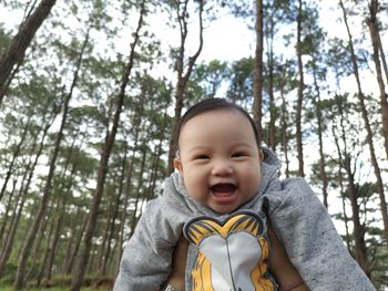 Portrait of smiling baby girl against trees