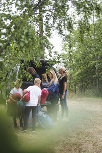 Family unloading luggage from car at camping site