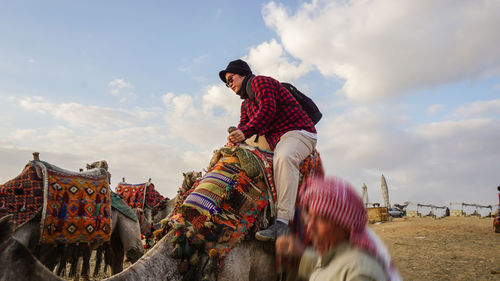 Asian woman tourist try to ride scary camel at pyramids of goza tour attraction of egypt