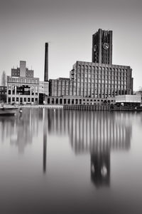 Reflection of buildings in river against sky