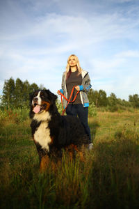 Woman with dog on field against sky