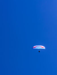 Low angle view of person paragliding against clear blue sky