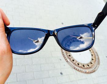 Close-up of hand holding sunglasses with reflection of berliner fernsehturm