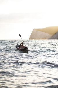 Man in boat on sea against sky