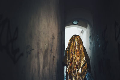 Person wrapped in golden paper walking in corridor