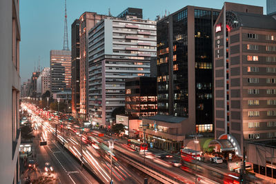 Light trails on city street amidst buildings