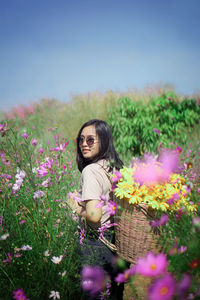 Woman standing by flowering plants on field