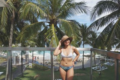 Full length of young woman in bikini standing by swimming pool