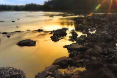 Rocks in sea during sunset