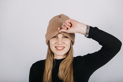 Unaltered candid emotional portrait of young happy woman with blonde long hair on grey background