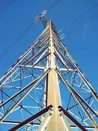 Low angle view of electricity pylon against blue sky