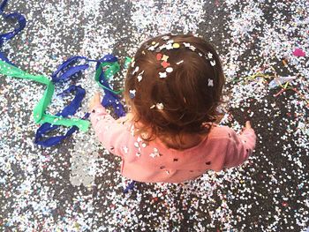 High angle view of child standing on street covered with confetti