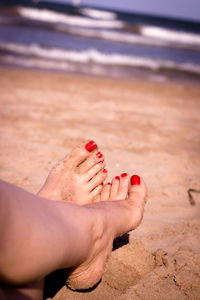 Low section of woman relaxing on sand at sandy beach
