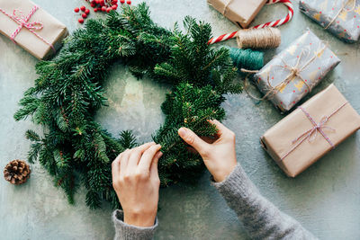 Female hands decorate the new year's wreath of branches of natural spruce. 