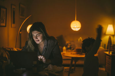 Young woman using laptop in living at home during night