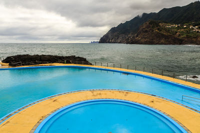 View of swimming pool by sea against sky