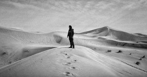 Rear view of man walking on sand dune