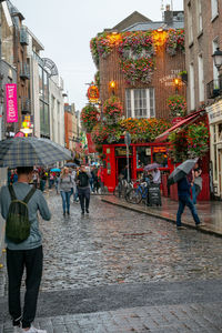 People walking on street in city during rainy season