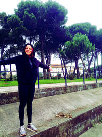 Portrait of smiling young woman standing against trees