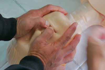 Cropped hands of paramedic practicing cpr on mannequin