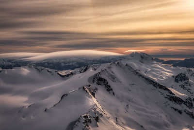 Scenic view of snow covered mountains against sky during sunset