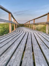 Surface level of wooden footbridge against sky