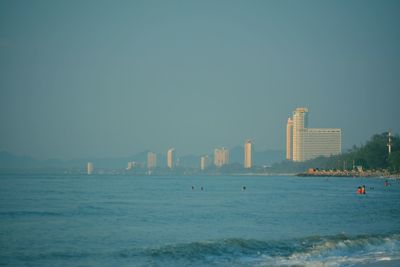 Sea by buildings against clear sky