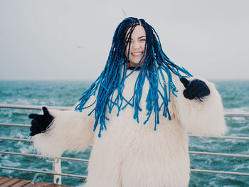 Portrait of woman tossing dyed dreadlocks on boat in sea