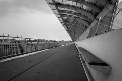 Bridge over road by buildings against sky