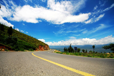 Road by trees against sky