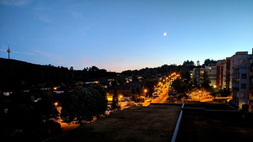 Illuminated street amidst buildings against sky at night