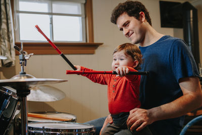 Father teaching baby boy to play drums. parent with toddler child having fun, spending time together