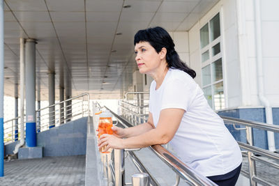 Side view of woman standing against railing