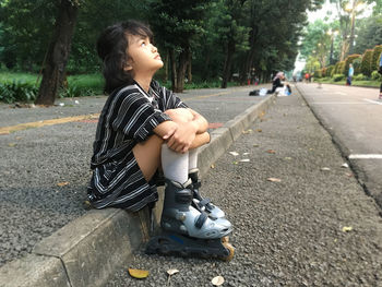Cute little girl with roller skates outdoors sits on the ramp