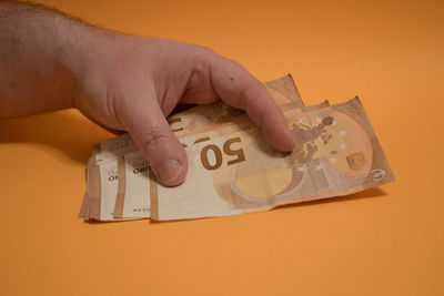 Midsection of person holding camera against orange background
