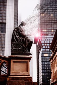 Low angle view of statue against buildings in city