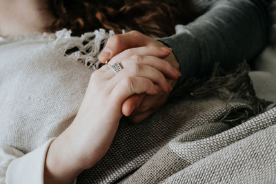 Cropped image of man holding hands with girlfriend lying on bed