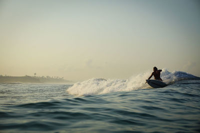 Man surfing in sea against clear sky