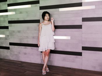 Woman looking away while standing against wall