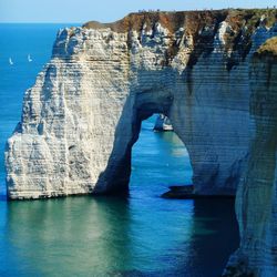 Rock formation by sea against sky