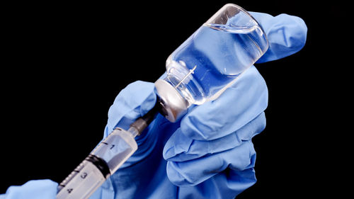 Midsection of person holding umbrella against black background