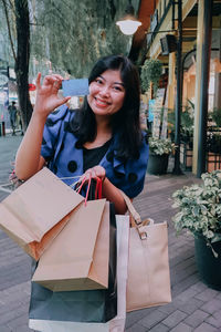 Beautiful fashionable asian woman a is shopping for a lot of goods at a mall using her credit card