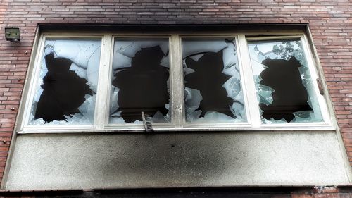 Low angle view of broken glass window on wall of building