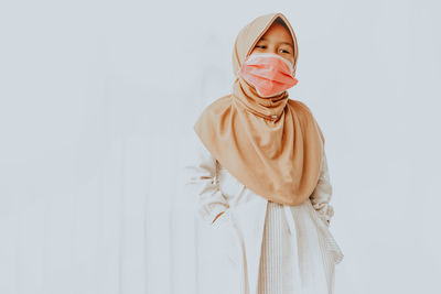 Portrait of young woman standing against white background