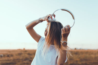 Woman holding umbrella while standing on land against sky