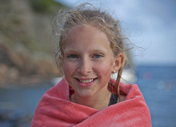 Portrait of smiling girl wrapped in towel at beach