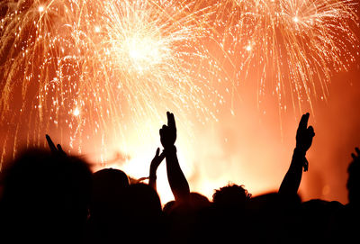 Silhouette people against firework display at night