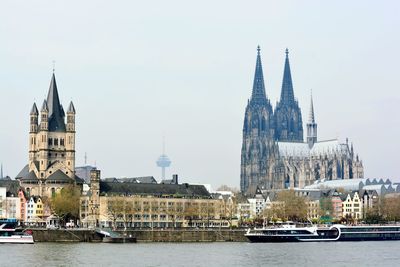 View of buildings by river in city against sky