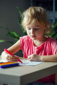 Cute girl drawing on book at home